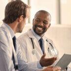 Physicians smile while holding computer and discussing EHR selection