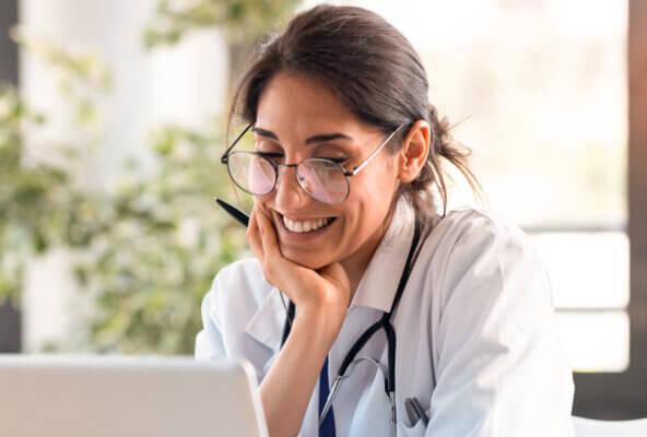 Physician reads April 2025 revenue cycle management healthcare news on laptop