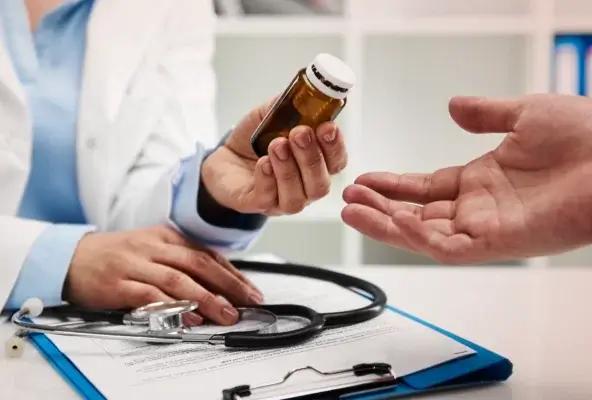 Healthcare provider holding a supplement bottle while discussing usage with a patient during a medical consultation.